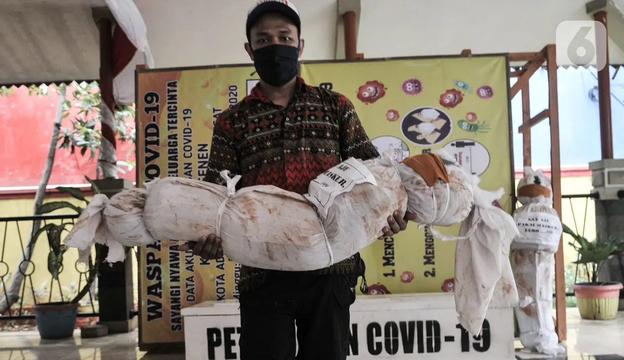 Pekerja mengendong boneka pocong untuk dipajang di Kantor Kecamatan Senen, Jakarta, Kamis (13/8/2020). Pemkot Jakpus menyiapkan peti mati dan boneka pocong di setiap kecamatan sebagai peringatan akan bahaya Covid-19 dan imbauan untuk tidak mengabaikan protokol kesehatan. (merdeka.com/Iqbal Nugroho)