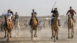 Tujuh peserta joki  bersaing dalam perlombaan balap unta lokal di Rafah, Jalur Gaza selatan (20/10/2019). Balapan unta ini menggunakan lintasan bekas landasan bandara Gaza yang sudah hancur di Rafah, Gaza selatan. (AFP Photo/Said Khatib)