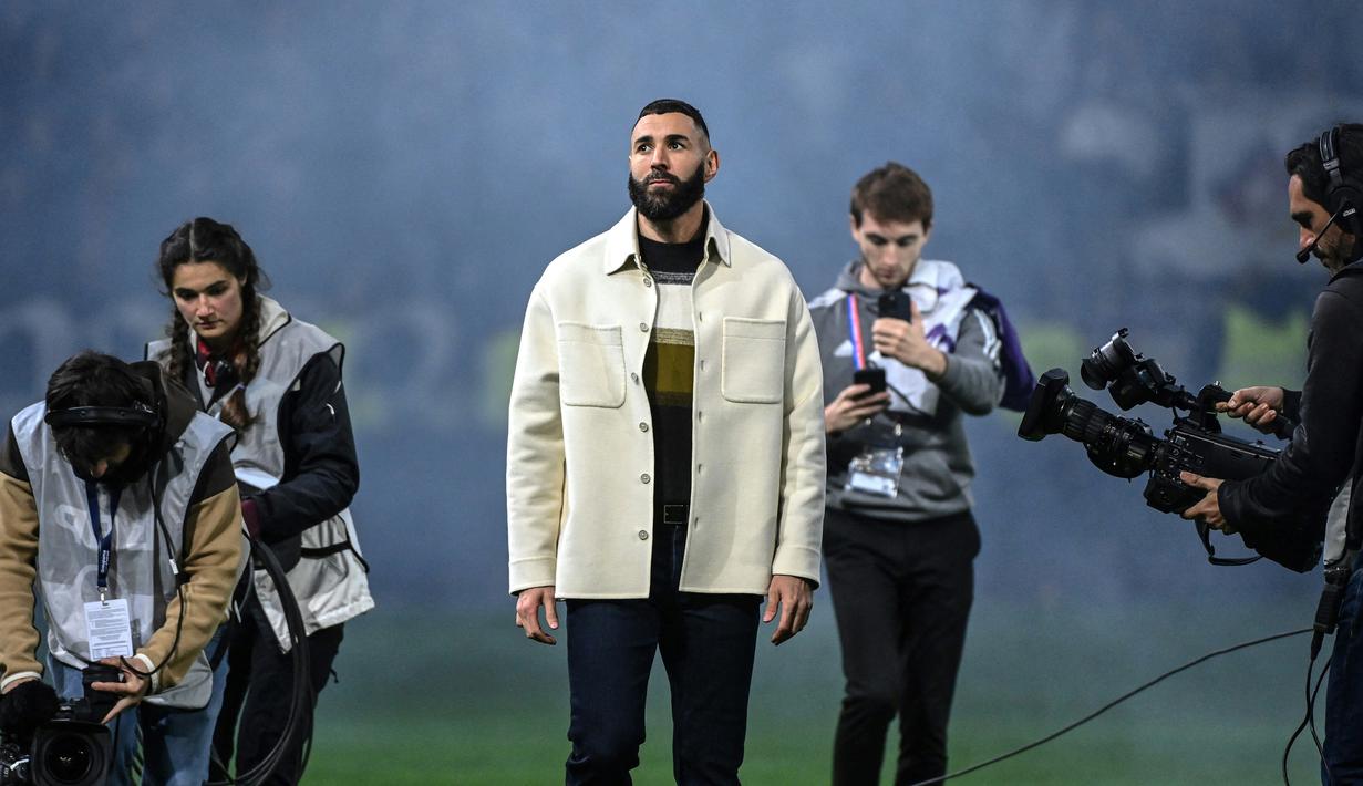 Pemain Real Madrid Karim Benzema (tengah) melihat para penggemar saat penyerahan trofi Ballon d'Or miliknya pada babak pertama pertandingan sepak bola L1 Prancis antara Olympique Lyonnais (OL) dan OGC Nice di Stadion Groupama, Decines-Charpieu, Prancis, 11 November 2022. Mantan striker Olympique Lyon tersebut menjumpai klub lamanya tiga pekan setelah memenangkan trofi Ballon d'Or. (OLIVIER CHASSIGNOLE/AFP)