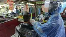 Tukang cukur mengenakan alat pelindung diri (APD) dari plastik saat mencukur rambut pelanggan di Pondok Kelapa, Jakarta, Selasa (5/5/2020). Tukang cukur mengenakan APD untuk mengurangi risiko penularan virus corona COVID-19. (merdeka.com/Imam Buhori)