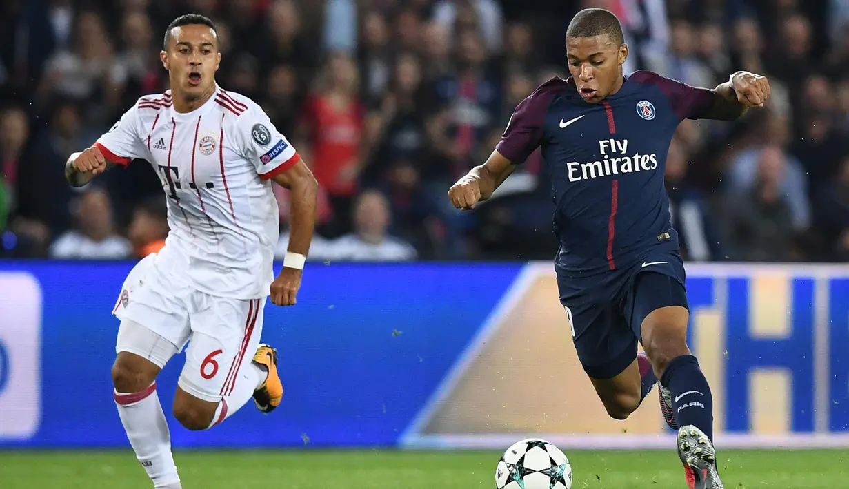 Penyerang PSG, Kylian Mbappe membawa bola dari kejaran gelandang Bayern Munchen Thiago Alcantara saat bertanding pada grup B Liga Champions di stadion Parc des Princes di Paris, Prancis (27/9). PSG menang telak 3-0 atas Munchen. (AFP Photo/Franck Fife)
