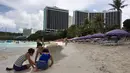 Sebuah keluarga bermain pasir di pantai Tumon, Guam, Kamis (10/8). Meskipun suasana ketegangan di kawasan itu meningkat terkait ancaman bom nuklir Korea Utara, warga Guam tetap beraktivitas seperti biasa. (AP Photo/Tassanee Vejpongsa)