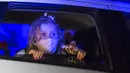 Seorang anak yang mengenakan masker menonton pertunjukan dari dalam mobil di taman hiburan horor Hopi Hari, pinggiran Vinhedo, Sao Paulo, Brasil, Jumat (4/9/2020). Karena pembatasan akibat COVID-19, taman hiburan horor Hopi Hari menampilkan pertunjukan secara drive-thru. (AP Photo/Carla Carniel)