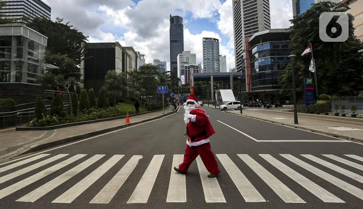 Pria berkostum Sinterklas menyeberang jalan saat membagikan kopi gratis kepada warga di kawasan Jalan Jenderal Sudirman, Jakarta, Sabtu (19/12/2020). Pembagian kopi tersebut bertujuan untuk menyambut perayaan Natal 2020. (Liputan6.com/Johan Tallo)