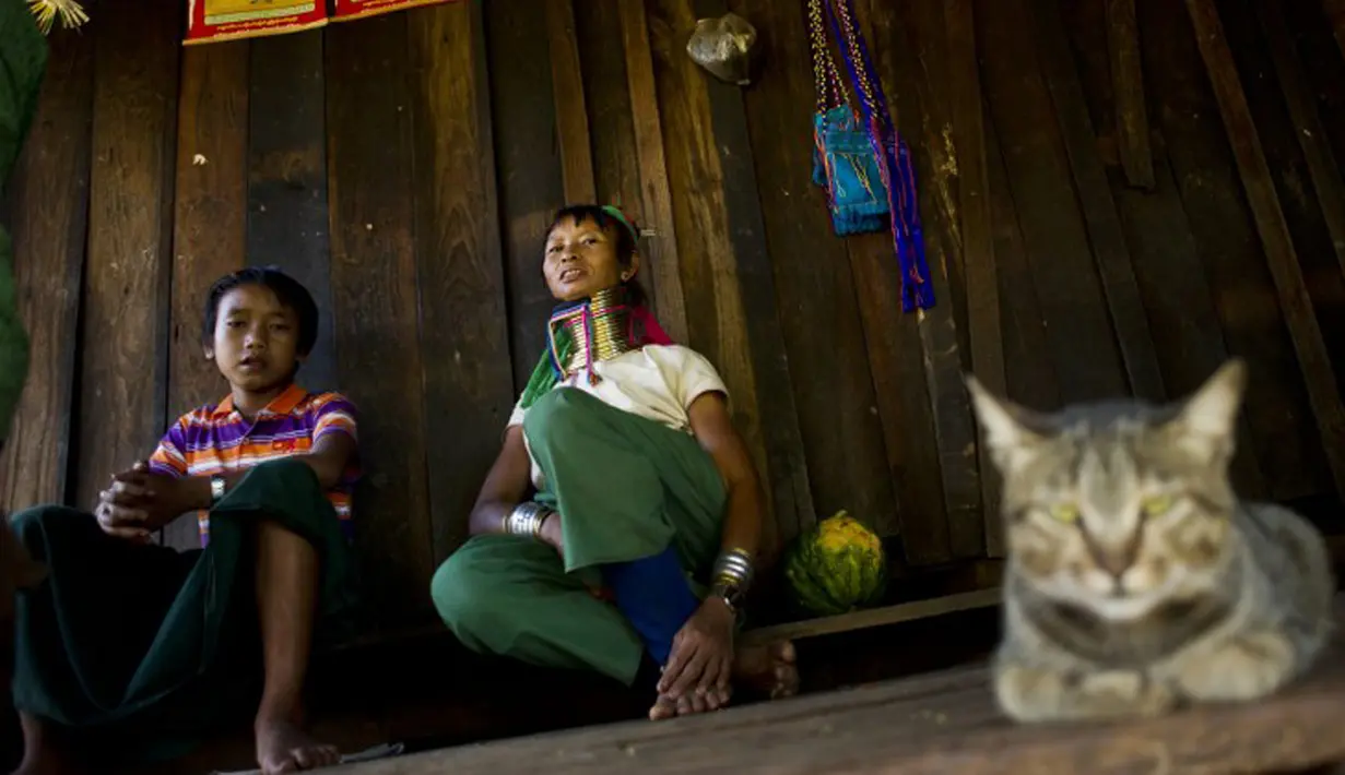 Wanita etnis Kayan saat bersantai di rumah mereka di desa PanPat, Kayan, Myanmar, Rabu (9/9/2015). Kaum perempuan Suku Kayan ini mengenakan banyak kalung berbentuk cincin di lehernya hingga membuat leher mereka panjang. (AFP PHOTO/Ye Aung THU)