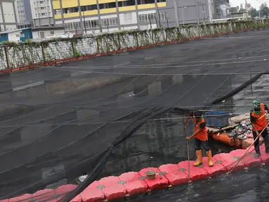 Petugas membersihkan Kali Item yang tertutup kain waring atau jaring di Kemayoran, Jakarta, Minggu (4/11). Sampah plastik, botol mineral, kaleng dan bungkus rokok bertebaran di waring yang membentang di atas Kali Item. (Liputan6.com/Immanuel Antonius)