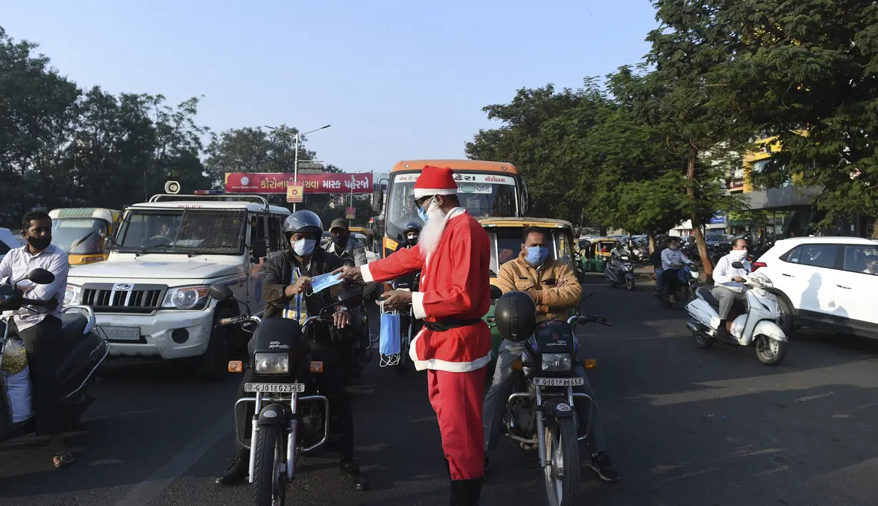 Presiden Angel Foundation dan pekerja sosial, Rufas Christian, berpakaian Sinterklas saat membagikan masker di persimpangan lalu lintas di Ahmedabad, India, Kamis (17/12/2020). Aksi itu sebagai bagian dari kampanye kesadaran melawan penyebaran virus corona COVID-19. (SAM PANTHAKY/AFP)