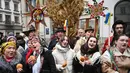 'Didukh' merupakan simbol Natal tradisional Ukraina. Tampak dalam foto, warga Ukraina yang mengenakan pakaian tradisional dan membawa hiasan tradisional Ukraina 'Didukh' menyanyikan lagu-lagu rohani saat mereka mengikuti prosesi Malam Natal di Lviv pada 24 Desember 2025. (YURIY DYACHYSHYN/AFP)