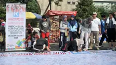 Pengunjung membubuhkan tanda tangan di atas spanduk raksasa saat car free day (CFD) di Bundaran HI, Jakarta, Minggu (22/7). Aksi ini merupakan dukungan masyarakat untuk kesuksesan pelaksanaan Asian Games 2018. (Merdeka.com/Iqbal Nugroho)