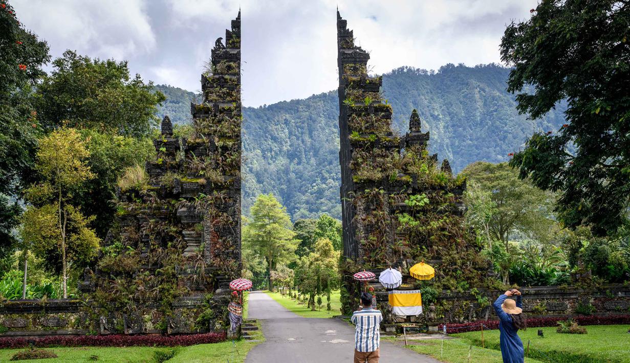 Pemandangan pura yang ikonik ini sangat dikenal oleh masyarakat Indonesia terlebih pernah diabadikan pada lembaran uang kertas pecahan Rp 50.000.-. Tampak dalam foto,wisatawan mengambil foto Gerbang Handara di dekat Bedugul, Bali, pada Jumat 7 November 2025. (Mladen ANTONOV/AFP)