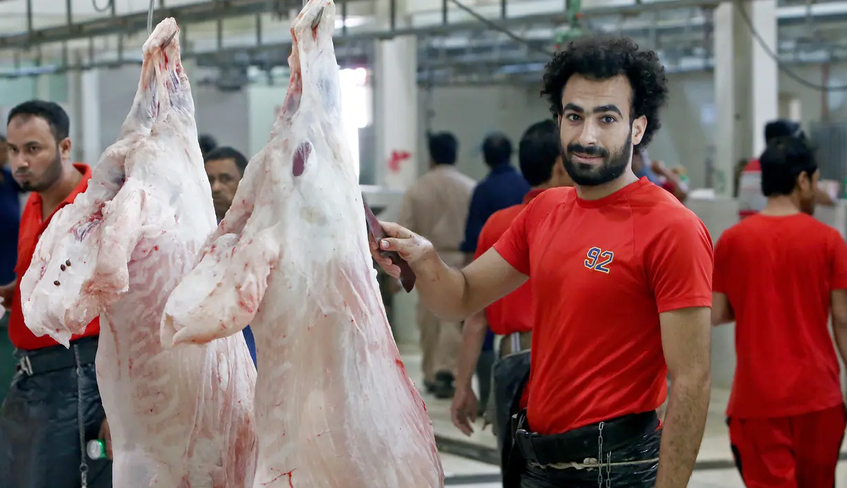 Mohammad Ibraheem saat memotong daging di sebuah rumah jagal hewan di hari ketiga Idul Adha di Kota Kuwait (13/8/2019). Pria 27 tahun ini mendadak terkenal karena kemiripan wajahnya dengan pemain Liverpool asal Mesir, Mohamed Salah. (AFP Photo/Yasser Al-Zayyat)