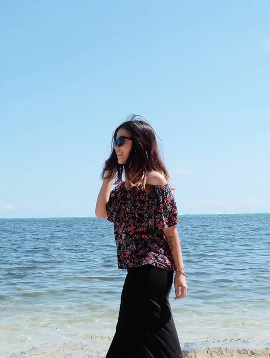 Gayanya kini semakin menawan. Seperti saat dirinya tampak bersantai di pantai. Meski memakai outif off shoulder dan rok hitam panjang. Dirinya tetap cantik dan menawan, ditambah kacamata hitam. (Liputan6.com/IG/@sisisinta)
