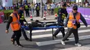 Meski beberapa robot sempat mengalami kendala teknis, mulai dari kesulitan memulai lomba hingga gagal mencapai garis finis. Tampak dalam foto, petugas keamanan dan peserta menggunakan tandu untuk membawa robot setelah robot tersebut berkompetisi dalam Beijing E-Town Half Marathon dan Humanoid Robot Half-Marathon di pinggiran Beijing, Minggu 19 April 2026. (AP Photo/Andy Wong)
