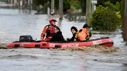 Pekerja darurat mengevakuasi penduduk dari properti yang terendam banjir di pinggiran Kota Melbourne, Maribyrnong, Australia, Jumat (14/10/2022). Curah hujan tinggi diprediksi akan terus terjadi. (William WEST/AFP)