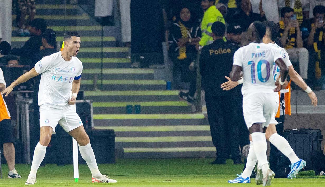Pemain Al Nassr, Cristiano Ronaldo, melakukan selebrasi setelah mencetak gol ke gawang Al Ittihad dalam laga tunda pekan ke-17 Liga Arab Saudi di King Abdullah Sport City Stadium, Jeddah, Rabu (27/12/2023). Kemenangan ini semakin istimewa lantaran CR7 mampu mencetak gol ke 53 nya di sepanjang tahun 2023. (Photo by AFP)