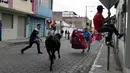 Seorang pria melemparkan jubahnya pada banteng muda dalam acara lari dikejar banteng di Pillaro, Ekuador, 4 Agustus 2018. Dalam acara ini, lusinan banteng dilepas dan berlari menabraki para pengunjung yang memadati jalan. (AP/Dolores Ochoa)