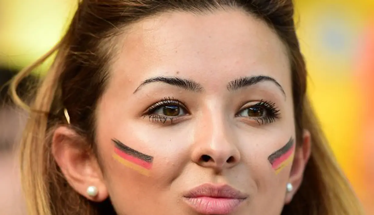 Suporter cantik Jerman ini rela menghias wajahnya sebelum Jerman berlaga melawan Ghana di The Castelao Stadium, Fortaleza (21/06/2014) (AFP PHOTO/JAVIER SORIANO)