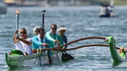Mantan atlet kano, Rubens Pompeu, membawa obor Olimpiade Rio dengan menaiki perahu di Danau Paranoa, Brasilia, Brasil, (3/5/2016). (AFP/Yasuyoshi Chiba)