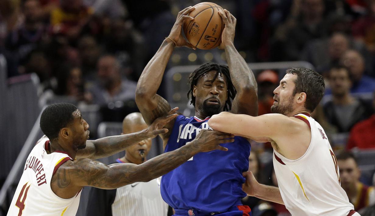 Pemain Los Angeles Clippers, DeAndre Jordan (tengah) berusaha melewati adangan dua pemain Cleveland Cavaliers pada laga NBA basketball game di Quicken Loans Arena, Cleveland, (18/11/2017), Cavs menang 118-113. (AP/Tony Dejak)