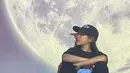 Tampil kasul serba hitam dengan topi, Ziva berpose candid di sebuah kafe unik yang berada di Chiangmai. Di sana, banyak spot foto yang unik dengan tema planet. Pelantun lagu 'Peri Cintaku' itu pun tak bisa melewatkan momen tersebut, dan segera bergaya untuk mengabadikannya dalam sebuah foto. (Liputan6.com/IG/@zivamagnolya)