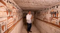 Kepala Dewan Tertinggi Kepurbakalaan Mesir, Mostafa Waziri memegang patung kecil di makam Henu, salah satu dari lima makam Firaun kuno di situs arkeologi Saqqara, Kairo, Mesir (19/3/2022). Menurut Waziri, lima makam yang semuanya dalam kondisi baik itu milik petinggi kerajaan. (AFP/Khaled Desouki)