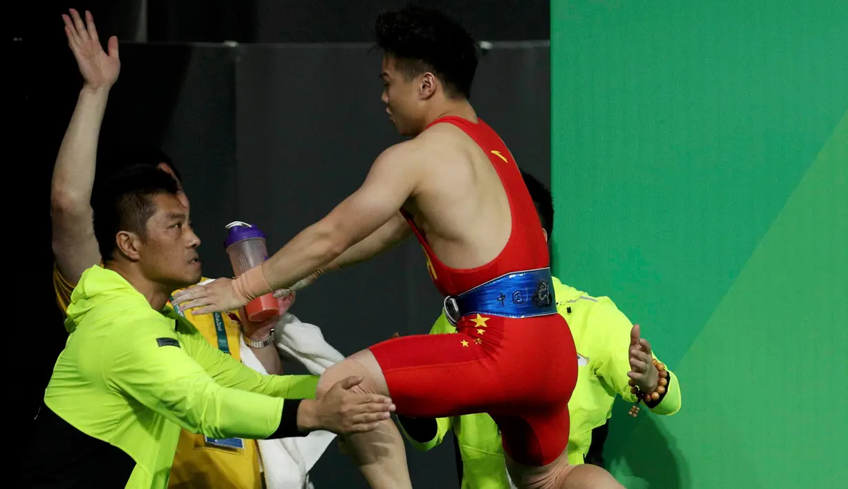 Lifter Tiongkok, Long Qingquan melompat ke pelatihnya setelah berhasil mengangkat beban pada cabang angkat besi putra selama Olimpiade Rio 2016 di Rio de Janeiro, Minggu (7/8). Long memecahkan rekor dunia usai menyabet medali emas. (REUTERS/Stoyan Nenov)