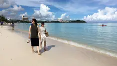 Pengunjung berjalan menyusuri tepi pantai Tumon di Guam, Kamis (10/8). Meskipun suasana ketegangan di kawasan itu meningkat  terkait ancaman bom nuklir Korea Utara, warga Guam tetap beraktivitas seperti biasa. (AP Photo/Tassanee Vejpongsa)