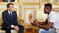 Presiden Prancis Emmanuel Macron (kiri) berbincang dengan Mamoudou Gassama di Istana Elysee, Paris, Prancis, Senin (29/5). Berkat kepahlawanannya, Macron menghadiahinya medali dan menawarinya kewarganegaraan Prancis. (AP Photo/Thibault Camus, Pool)