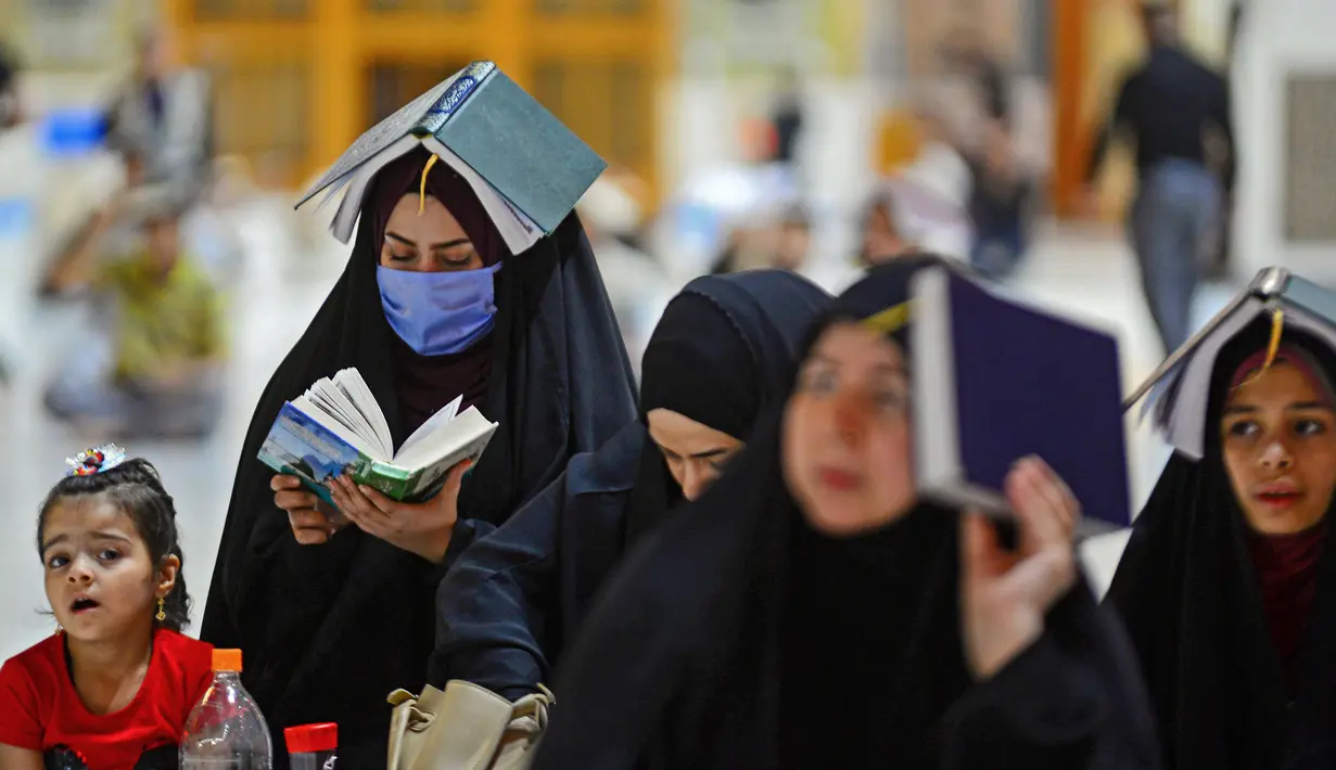 Para jemaah syiah manaruh kitab suci Al-Quran di atas kepala mereka saat menyambut malam lailatul qadar di Makam Suci Imam Ali, Najaf, Irak, Sabtu (16/5/2020). Ritual saat berdoa dan meminta hajat kepada Tuhan ini sudah berlangsung selama berabad-abad lamanya. (HAIDAR HAMDANI/AFP)