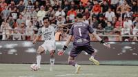 Pemain Bali United, M. Rahmat, ketika berhadapan dengan kiper Semen Padang, Arthur, dalam laga pekan ke-19 BRI Liga 1 2024/2025 di Stadion H. Agus Salim, Padang, Senin (20/1/2025) sore WIB. Bali United menang 5-1 dalam laga ini. (Bola.com/Alit Binawan)