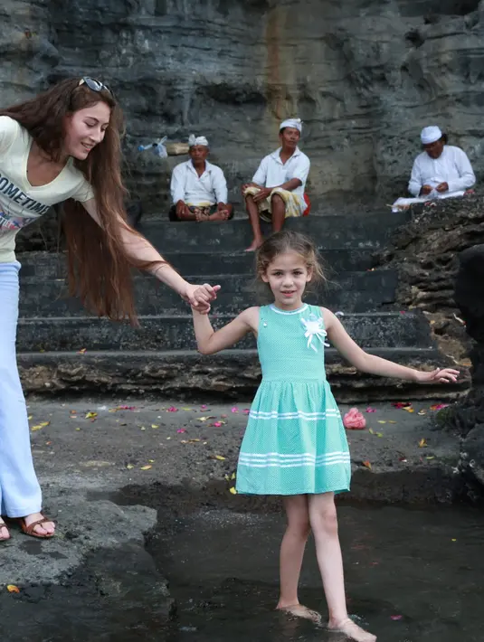 Isabella dan kakaknya asyik menikmati indahnya Tanah Lot, setelah minum air suci mereka melakukan foto bersama, para penggemar pun tidak ingin melewatkan kesempatan tersebut. (Deki Prayoga/Bintang.com)