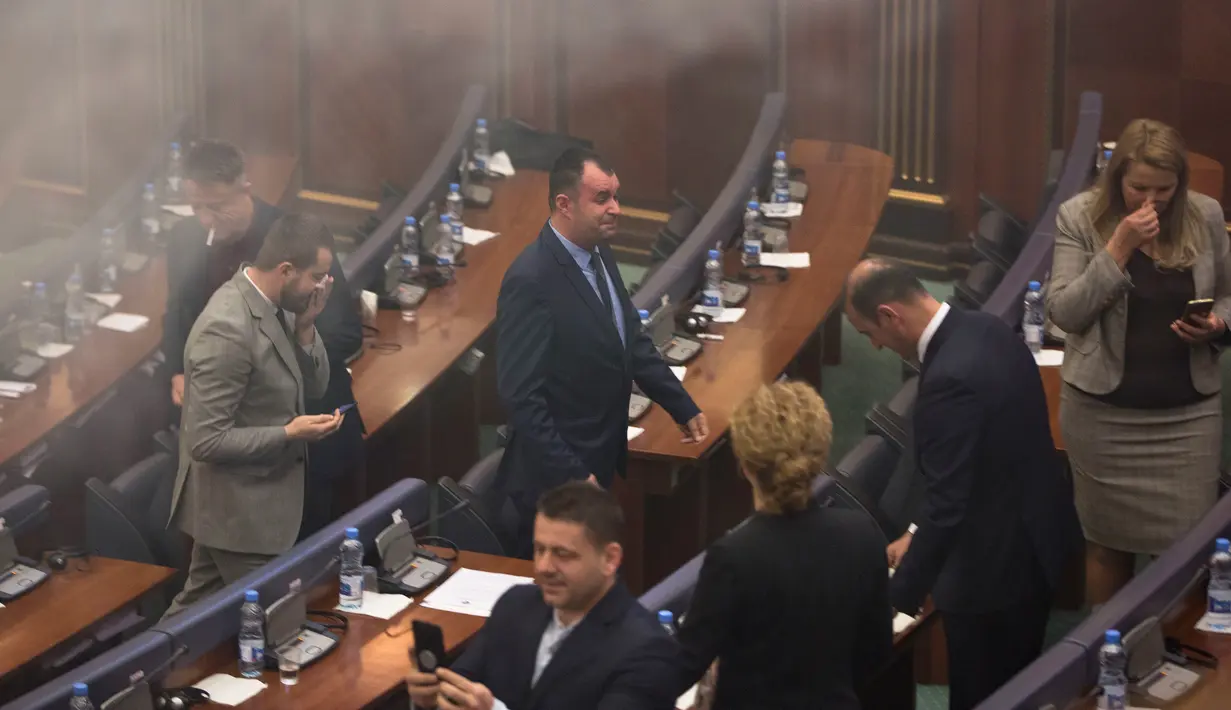Para politisi meninggalkan ruangan yang dipenuhi asap gas air mata dalam rapat parlemen di ibu kota Kosovo, Pristina, Rabu (21/3). Aksi pelemparan kaleng gas air mata tersebut dilakukan oleh seorang anggota Partai Vatevendosje. (AP Photo/Visar Kryeziu)