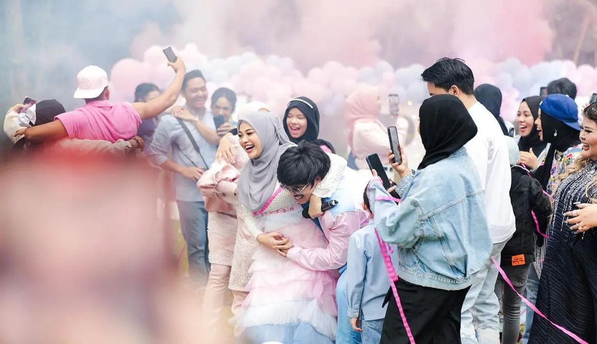 Aurel tampak mengenakan tiered tulle dress nuansa biru-pink pastel, dipadukan dengan hijab warna soft grey.