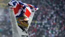 Lewis Hamilton membentangkan bendera negaranya saat merayakan kemenangannya meraih juara dunia F1 untuk yang ke empat kalinya di Autodromo Hermanos Rodrigue, Meksiko (29/10). (AP Photo / Moises Castillo)