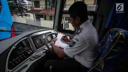 Petugas duduk dalam bus Transjabodetabek Premium saat menunggu calon penumpang di Tamini Square, Jakarta, Kamis (14/12). Kapasitas bus tersebut dapat menampung 41 penumpang dan dilengkapi fasilitas penunjangnya. (Liputan6.com/Faizal Fanani)