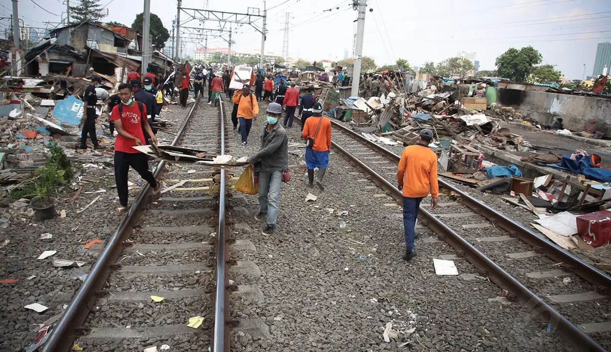Petugas memindahkan puing bangunan liar usai pembongkaran di pinggiran rel kawasan Tanah Abang, Jakarta, Kamis (7/8/14). (Liputan6.com/Faizal Fanani)