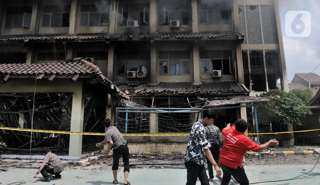 Sejumlah guru, pegawai, dan siswa mencoba memecahkan kaca dengan batu saat berusaha memadamkan api yang kembali muncul di Gedung SMK Yadika 6, Jatiwaringin, Pondok Gede, Kota Bekasi, Jawa Barat, Selasa (19/11/2019). Api muncul di salah satu ruang yang berada di lantai 2. (merdeka.com/Iqbal Nugroho)