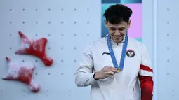 Atlet panjat tebing Indonesia, Veddriq Leonardo memandangi medali emasnya saat di atas podium cabang olahraga panjat tebing nomor speed Olimpiade Paris 2024 di Le Bourget Sport Climbing Venue, Paris, Prancis, Kamis (08/08/2024). (AFP/Jonathan Nackstrand)