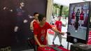 Seorang pekerja mengarahkan fans Arsenal untuk berfoto dengan gambar dua pemain The Gunners di Beijing, Jumat, (21/7/2017). Arsenal dan Chelsea akan bertanding dalam laga persahabatan. (AP/Ng Han Guan)