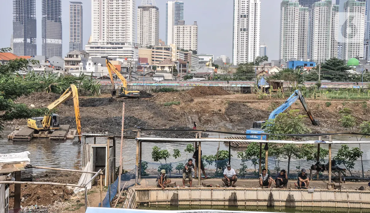 Warga memancing dekat kendaraan alat berat yang tengah mengerjakan pengerukan lumpur di Kali Ciliwung Segmen Kanal Banjir Barat (KBB), Tanah Abang, Kamis (30/9/2021). Pengerukan dilakukan untuk memperbesar daya tampung sekaligus mengantisipasi banjir pada musim hujan. (merdeka.com/Iqbal S. Nugroho)