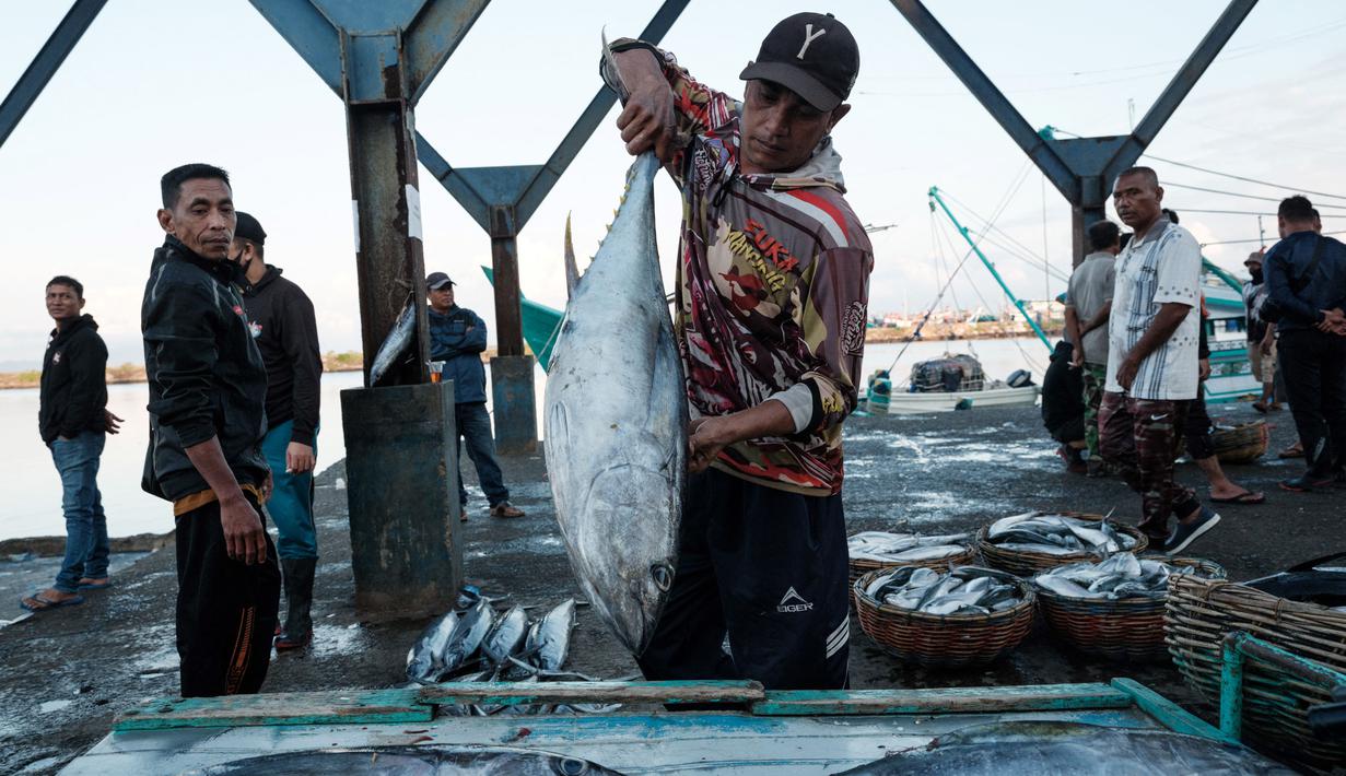 Seorang pria memuat ikan ke atas kapal motor di Pelabuhan Perikanan Samudera Lampulo, Banda Aceh, pada 27 Desember 2024. (Yasuyoshi CHIBA/AFP)