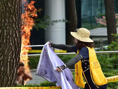 Wanita menolong Pria yang membakar dirinya sendiri depan Kantor Kedubes Jepang, Seoul, Korea Selatan, Rabu (12/8/2015). Aksi ini bentuk protes terhadap pemerintah Jepang yang selama Perang Dunia II memaksa wanita korea bekerja. (AFP PHOTO/JUNG YEON-JE)