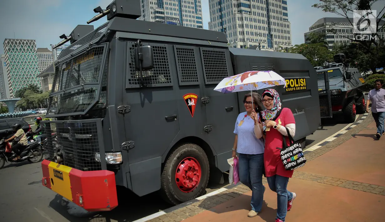 Pejalan kaki melintas di samping kendaraan taktis milik Brimob yang disiagakan di sekitar bundaran Patung Kuda, Jakarta, Jumat (28/7). Kendaraan taktis disiapkan untuk mengamankan aksi 287 yang digelar Presidium Alumni 212. (Liputan6.com/Faizal Fanani)