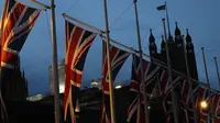 Bendera Inggris berkibar dengan latar Istana Westminster terlihat di London, Sabtu, (1/2/2020).  Mulai 1 Februari 2020 ini, Inggris secara resmi telah meninggalkan Uni Eropa (UE) setelah lebih dari tiga tahun referendum yang membuat negara itu terpecah belah. (AP Photo/Alastair Grant)