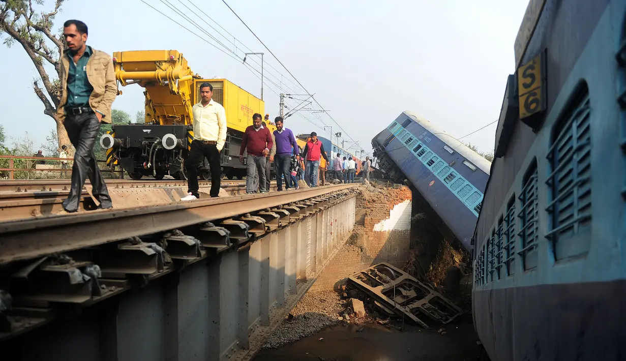 Sejumlah orang melihat kondisi kereta api yang tergelincir di Kanpur, India utara, Rabu (28/12). Peristiwa tersebut mengakibatkan 2 orang tewas dan 43 lainnya luka-luka. (AFP PHOTO / SANJAY Kanojia)
