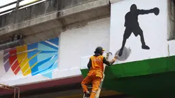 Penataan ini melibatkan untuk memastikan area yang sebelumnya kumuh menjadi rapi dan layak digunakan masyarakat sebagai ruang terbuka publik. Tampak dalam foto, salah satu petugas Penanganan Prasarana dan Sarana Umum (PPSU) melakukan pengecatan di sisi jembatan layang Pasar Rebo, Jakarta Timur, Jumat (8/5/2026). (Kapanlagi.com/Budy Santoso)