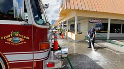 Petugas pemadam membersihkan noda darah di lokasi penembakan di tempat parkir Club Blu di Fort Myers, Florida, Senin (25/7). Pria bersenjata melepaskan tembakan ke arah kerumunan orang yang berada di tempat parkiran klub malam itu. (REUTERS/Joe Skipper)