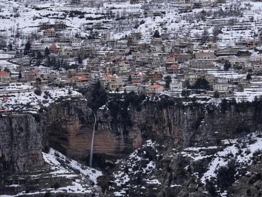 Kota Bcharre yang tertutup salju, menghadap ke lembah Qadisha di gunung Lebanon, di utara ibu kota Beirut (22/2/2022).(AFP/Ibrahim Calhoub)