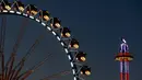 Pengunjung menikmati wahana taman hiburan di belakang kincir raksasa saat festival Oktoberfest di Munich, 27 September 2018. Oktoberfest adalah rangkaian festival terbesar di dunia yang diadakan setiap tahun oleh masyarakat Jerman. (AP/Matthias Schrader)