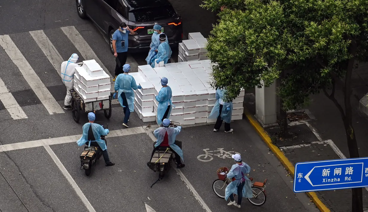 Pekerja yang mengenakan alat pelindung diri berdiri dekat kotak yang akan dikirim saat perberlakuan lockdown karena virus corona COVID-19 di Distrik Jing'an, Shanghai, China, Rabu (18/5/2022). (Hector RETAMAL/AFP)